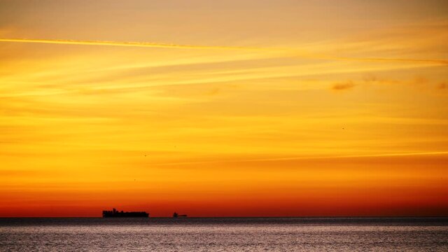 Seascape at sunrise with cargo container industrial ships stand in the roadstead on Gibraltar Strait, view from spanish coast. Logistic shipping concept.