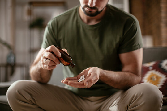 Young man drink medicine pill. Close up of man hands holding pill.
