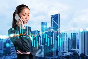 Attractive Asian businesswoman trader processing conference call to forecast the capital market behavior. Concept of trading strategy. Forex chart. Kuala Lumpur. Double exposure. - Powered by Adobe