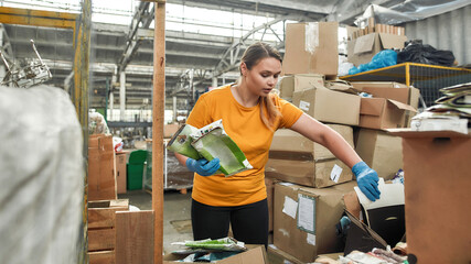Cheerful young woman collecting tetra packs waste paper