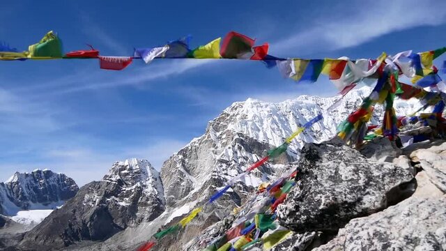 Multi-colored Buddhist prayer flags waving in strong wind on the summit of Kala Patthar, Khumbu region, Nepal in the Himalayas with snow-capped mountains on sunny day.