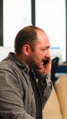 Nervous manager aggressively talking on phone and curses, screaming sitting on chair in middle of business office. Multiethnic scared coworkers planning financial project working in modern company