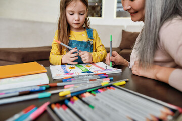 Happy little girl drawing in album with grandmother