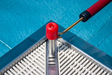 detail of a corner of a swimming pool with blue water and red bracket
