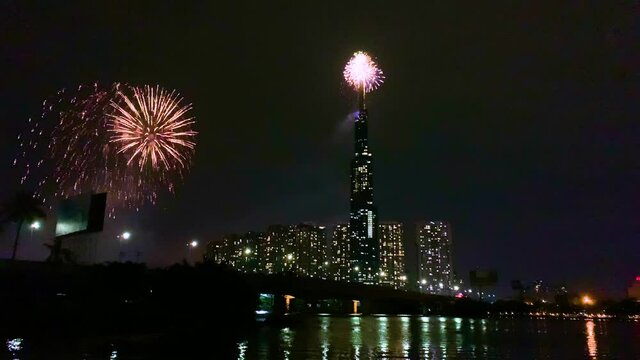 High resolution footage of colorful fireworks of Ho Chi Minh City at new year 2021 view from Landmark 81 riverside. Landmark 81 is the tallest building in Vietnam