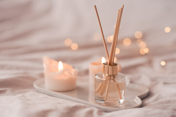 Obraz na płótnie Canvas Home aroma fragrance diffuser with burning candles on white tray in bed over glowing lights close up. Cozy atmosphere. Wellness. Healthy lifestyle.