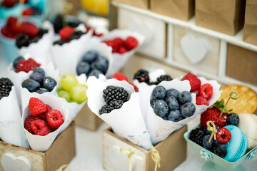 A table with delicacies-macaroons,  berries, biscuits, grapes in bags.