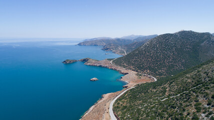 Beautiful landscape of the island from a bird's-eye view. Blue sea, clear sky, road, rocks, cliff and green mountains.