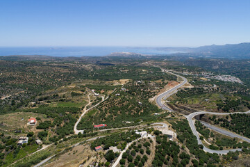 Fototapeta na wymiar Beautiful scenery of the island from a bird's-eye view. A view of the city, houses, roofs of houses and roads passing through green mountains and hills.