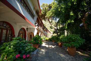 Obraz premium A view of the road and a great monastery surrounded by flowerpots with flowers and greens.
