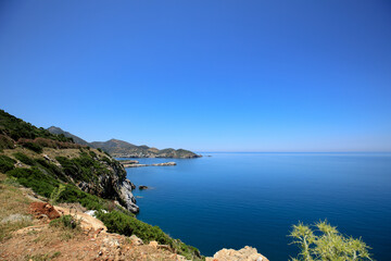 A view of the beautiful island is the blue sea and sky, green mountains and plantations of olive trees.