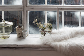 Cozy winter still life. Dried plants, small coffee cups and warm fur on vintage kitchen windowsill. Winter season, spending winter time at cozy home concept