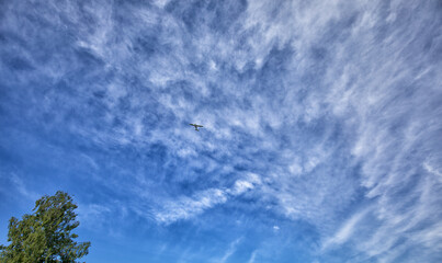  A flying plane in a blue sky with clouds.
