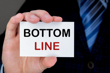 Business man handing a visiting card with BOTTOM LINE on it.
