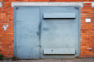 Blue metal doors and gates to a brick garage