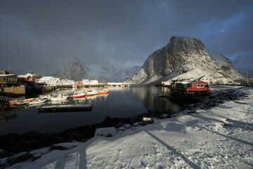 Beautiful landscape. Lofoten Islands. Red houses and boats against the backdrop of mountains and clouds.