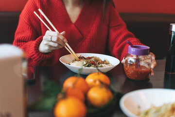 Beautiful smiling young asian woman in red clothes eating asian food in chinese vietnamese restaurant