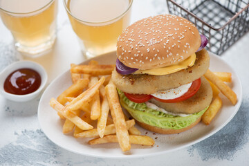 White plate with double fishburger, french fries and beer over white concrete background, studio shot