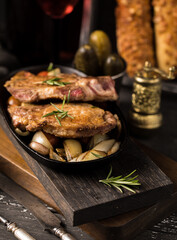 Tasty food. Frying pan with fried meat and onions, gherkins and French baguette