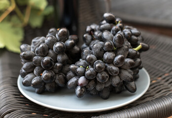 A bunch of ripe blue grapes in a gray container on a black background.