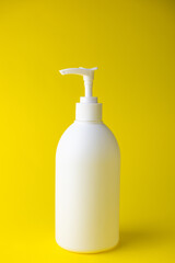 White unbranded dispenser bottle isolated on yellow background, cosmetic packaging mockup with copy space