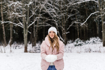 Fototapeta na wymiar young beautiful woman among snow trees holding snow
