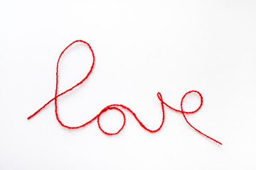 Valentine's day concept. Red heart and word love made from woolen rope on white background with copy space.