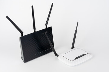 Two Wi-Fi  routers, wireless devices with two and three antennas.  Black router has five Gigabit Ethernet ports, ultrafast USB 3.1 port and  USB 2.0 port.  - obrazy, fototapety, plakaty