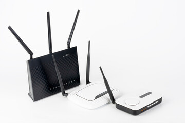Three  Wi-Fi  routers, wireless devices with one, two and three antennas.  Black router has five Gigabit Ethernet ports, ultrafast USB 3.1 port and  USB 2.0 port. 
