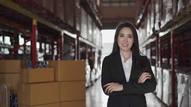 Asian businesswoman entrepreneur in suit and inventory goods stock on shelf in distribution retail warehouse fulfillment center. eCommerce, global business and freight logistic industrial concept.