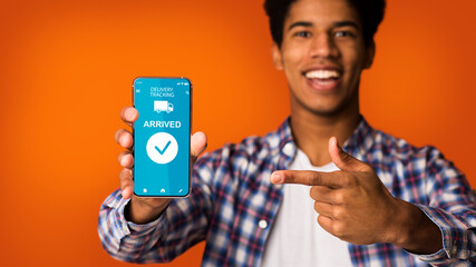 Black man pointing at smartphone with delivery tracking website