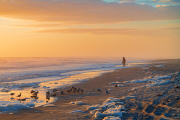 The dawn rises on a sea foam covered beach in Daytona Florida.