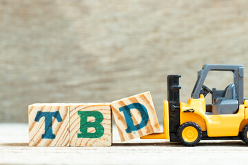 Toy forklift hold letter block d to complete word TBD (Abbreviation of to be defined, discussed,...