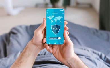 Young man holding and using cellphone with vpn app