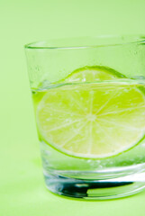 Limettenscheibe im Wasserglas vor gr¸nem Hintergrund