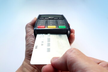 credit card is inserted by right hand into the credit card reader machine isolated on white background for paying process at the grocery shop , retail, department store by credit card