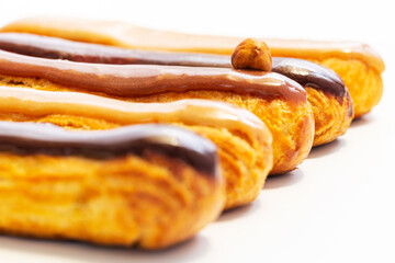 Hazelnut, caramel and chocolate French eclair pastry. Shallow depth of field with focus on the middle hazelnut one. Infinite white background Art concept.