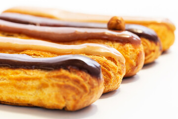 Hazelnut, caramel and chocolate French eclair pastry. Very shallow depth of field with focus on middle. White background Art concept.
