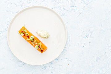 Raw salmon with apple, edible flowers, zucchini and beetroot on a white and blue plate aside silver cutlery and a quenelle of cheese with dill over a blue background with copy space.