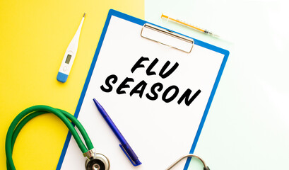 A sheet of paper with text FLU SEASON, stethoscope and medication.