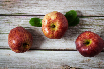 Large red apples lie on a wooden table