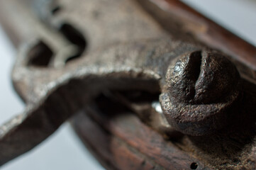 Close up detail of a silver flintlock mechanism with an engraved pattern on an old wooden pistol