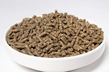 Compound feed for rabbits in a plate on a white background. Rabbit food, balanced pet food. Meals for meat rabbits.