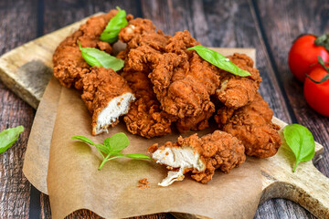 
 Crispy  deep fried   chicken strips. Breaded  with cornflakes chicken  breast fillets  with chilly peppers and fresh   basil on wooden rustic background