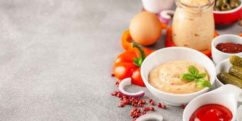 Thousand Islands sauce and ingredients - cucumbers, onions, paprika, ketchup and mayonnaise in bowls on the table. American cuisine, dip for burgers and meat.