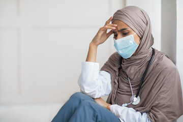 Fatigued physician young woman in hijab resting at her cabinet