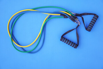 Resistance band exercise on blue background, copy space.