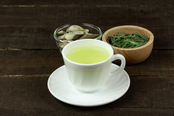 Lemon grass tea in white cup and lemon grass sliced with green leaf on wooden background. Healthy herbal drink concept.
