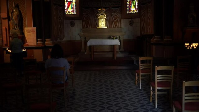 People sitting inside the Catholic church. St. Leo Chapel. Eguisheim, Alsace, France. Filming in 4k. Cinematic view.