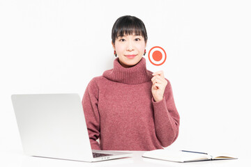 パソコンを使いながらOKのプラカードを持つ女性